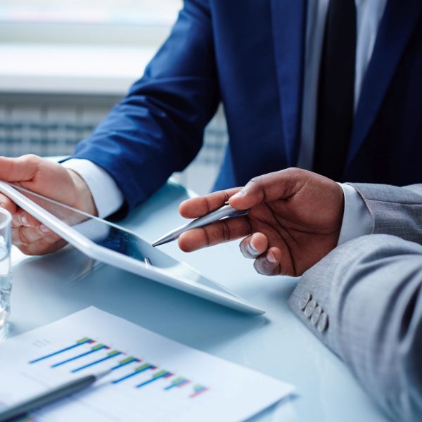 Image of businessmen discussing data in touchpad at meeting