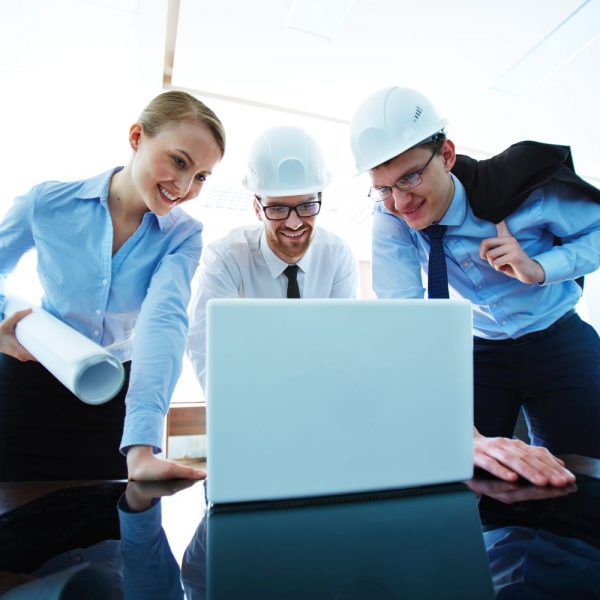 Group of young architects looking at laptop display in office