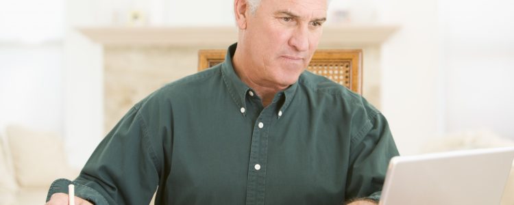 Man in dining room with laptop and paperwork