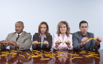 Stressed people breaking pencils in office