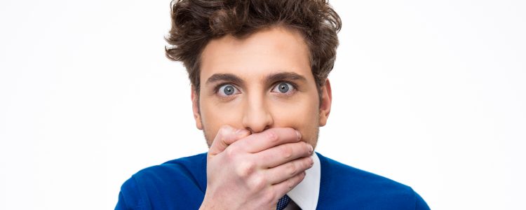 Portrait of a young man covering his mouth over white background