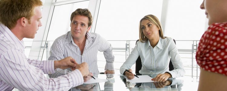 Four businesspeople in a boardroom with paperwork