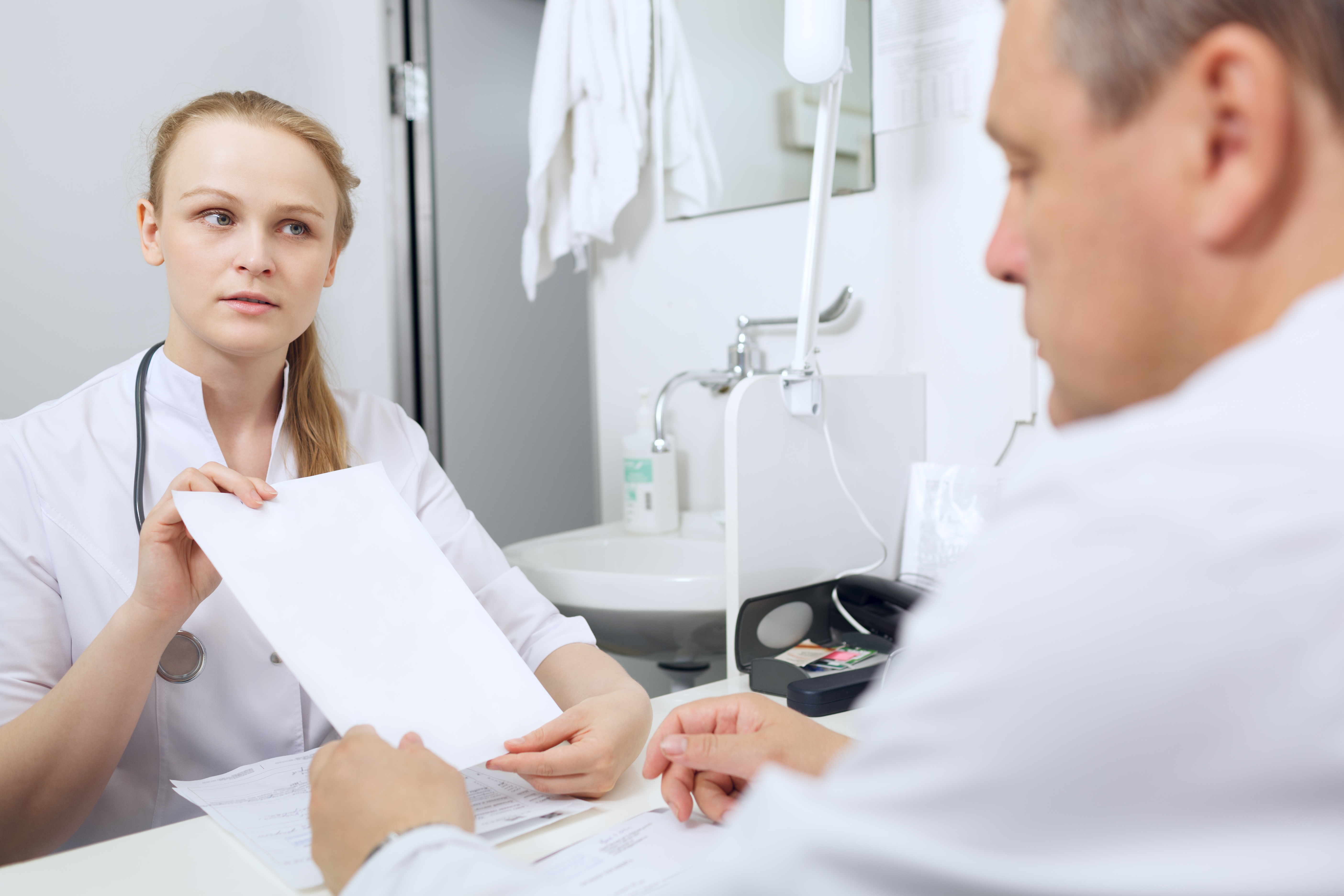 Nurse shows to the doctor blank sheet of paper