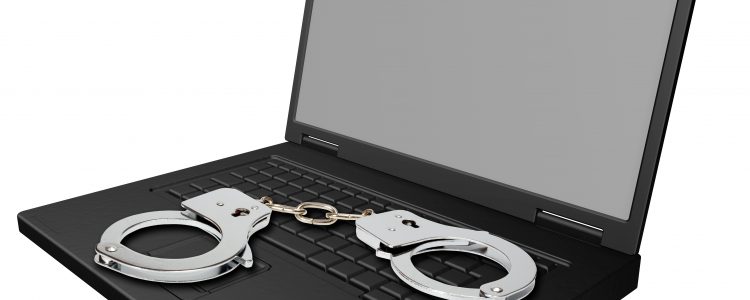 Laptop isolated on white with handcuffs.